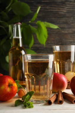 Elma şarabı, tarçın ve ahşap arka planda elmalarla kompozisyon