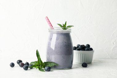 Beyaz masada bir bardak çilekli milkshake. Yaz içeceği