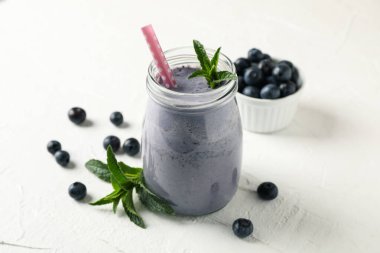 Beyaz masada bir bardak çilekli milkshake. Yaz içeceği