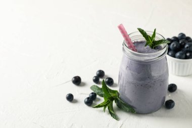 Beyaz masada bir bardak çilekli milkshake. Yaz içeceği