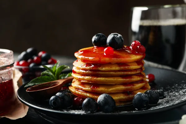 Plate of tasty pancakes with berry and powder on wooden table. Composition of sweet breakfast