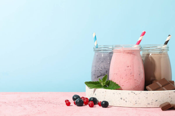 Tray with delicious milkshakes against blue background. Summer drink