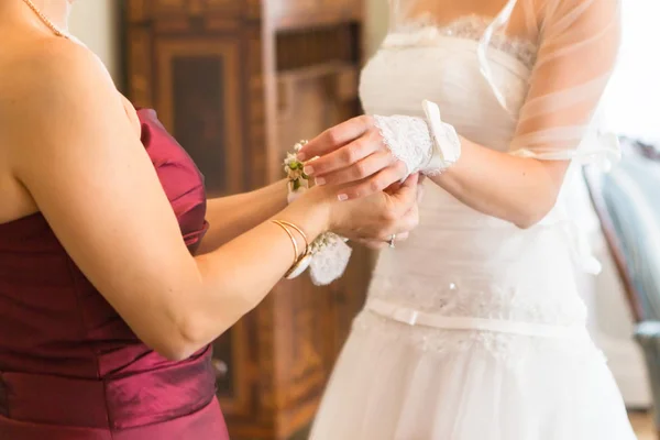 Dama de honor está ayudando a la novia a abotonar el vestido de novia —  Fotos de Stock