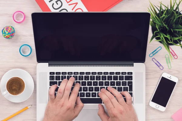 Κορυφαία προβολή Flat Lay χώρο εργασίας μαέλα με το iPhone smartphone και ανοιχτό φορητό υπολογιστή MacBook με Man χέρια στο γραφείο γραφείου — Φωτογραφία Αρχείου