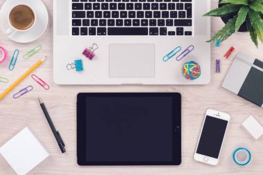 Macbook dizüstü bilgisayar klavyesi, ipad tablet pc ve iphone akıllı telefon üst görünümü ile Ofis masası masa işyeri