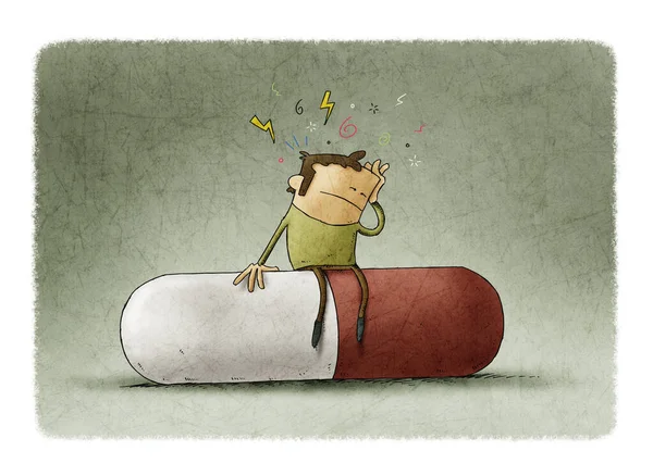 Человек с симптомами головной боли сидит на огромной таблетке — стоковое фото