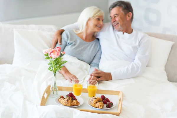 Ανώτερος ζευγάρι, απολαμβάνοντας το πρωινό στο κρεβάτι — Φωτογραφία Αρχείου