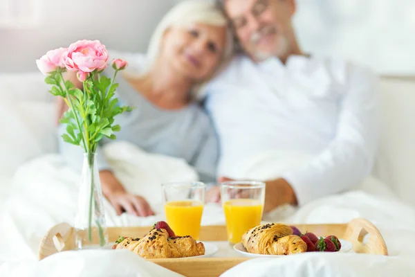 Casal sênior desfrutando de café da manhã na cama — Fotografia de Stock