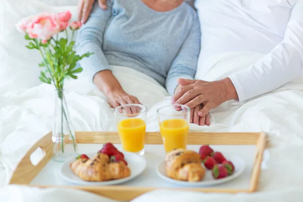 Senior koppel genieten van ontbijt op bed — Stockfoto