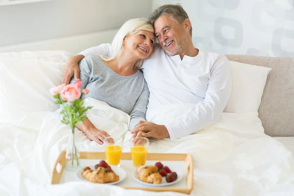 Casal sênior desfrutando de café da manhã na cama — Fotografia de Stock