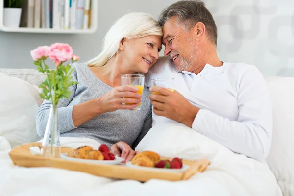 Старшая пара наслаждается завтраком в постели — стоковое фото