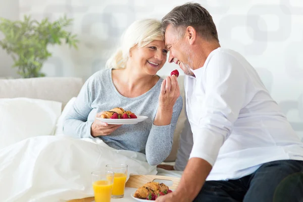 Старшая пара наслаждается завтраком в постели — стоковое фото