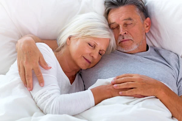 Старшая пара, лежащая вместе в постели — стоковое фото