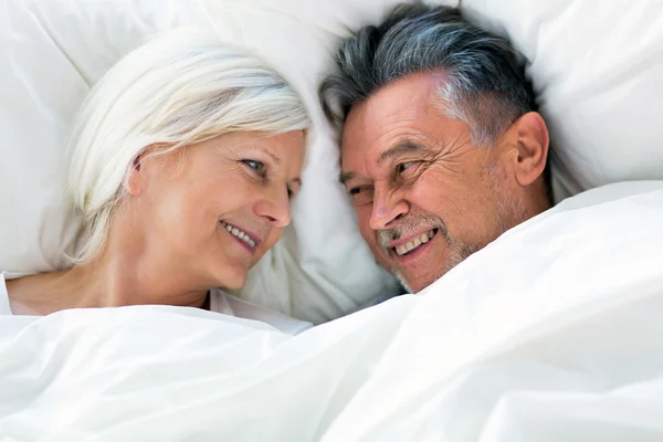 Starší pár ležící spolu v posteli — Stock fotografie