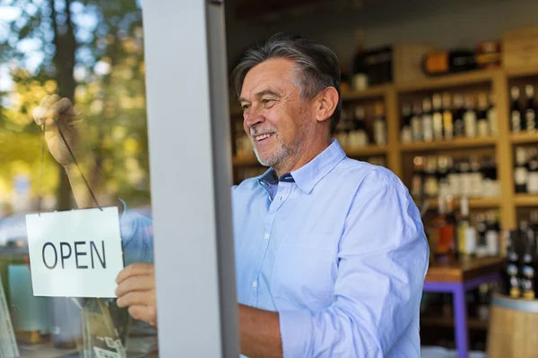 Wine shop owner holding open sign — ストック写真