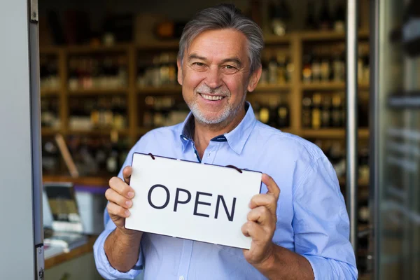 Wine shop owner holding open sign — ストック写真