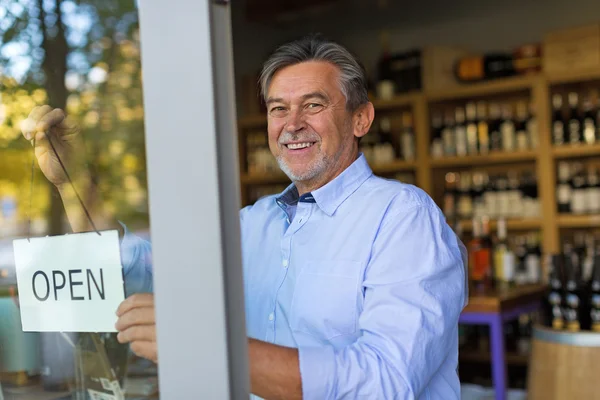 Wine shop owner holding open sign — Stockfoto