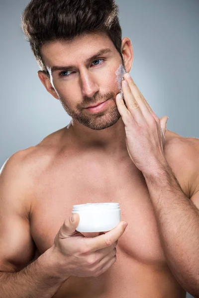 Homem aplicando creme facial — Fotografia de Stock