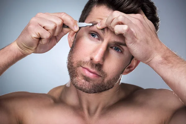 Mann zupft mit Pinzette Augenbrauen — Stockfoto