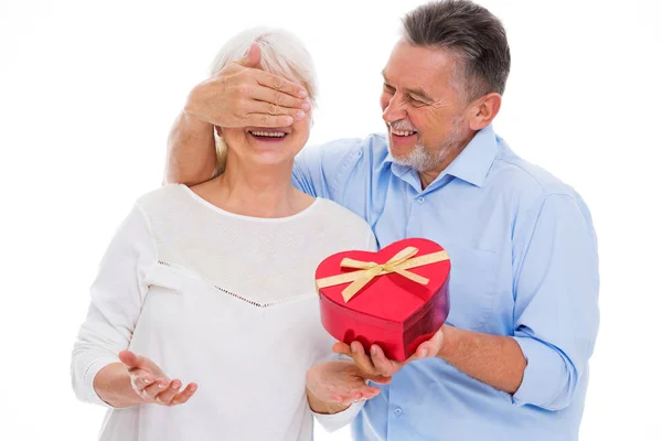 年配の男性が女性の目を覆うと、ハート型の箱を持って — ストック写真