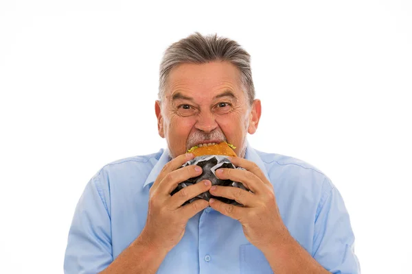Senior Mann isst Hamburger Stockbild