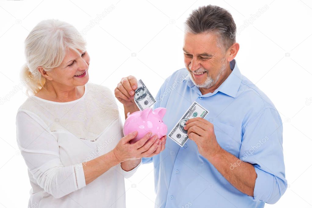 Senior couple holding money and piggy bank