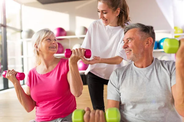 Entrenamiento de pareja mayor en el gimnasio con un entrenador personal — Foto de Stock