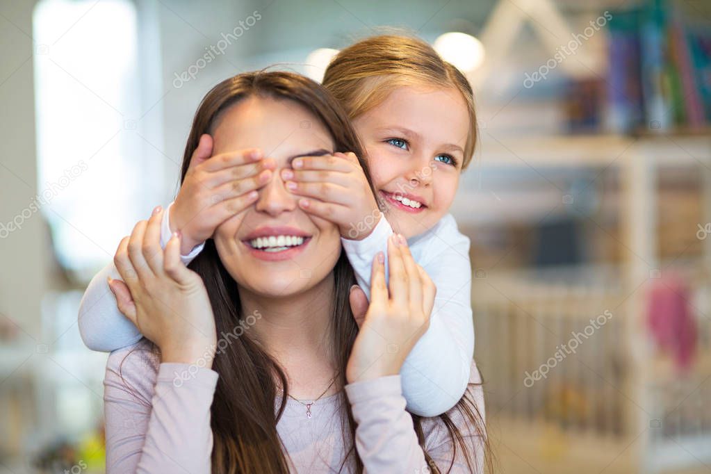 Happy little girl cover her mother eyes