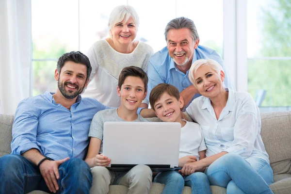 Família usando laptop em um sofá — Fotografia de Stock