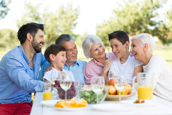 Familie sitzt am Tisch im Freien und lächelt — Stockfoto