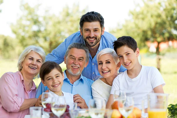 Familjen sitter vid bord utomhus, leende — Stockfoto