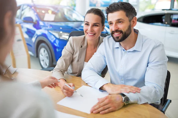 Νεαρό ζευγάρι με τον έμπορο αυτοκινήτων στο auto salon — Φωτογραφία Αρχείου