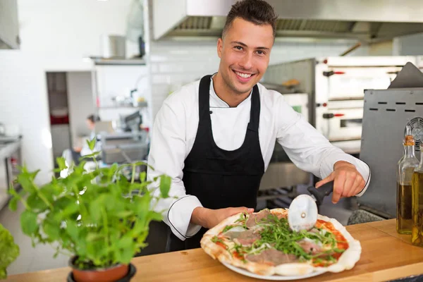 Szef uśmiechający się przygotowanie pizzy w kuchni — Zdjęcie stockowe