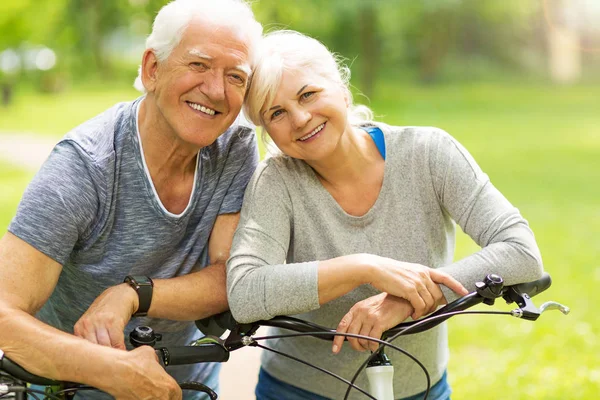 Pareja de ancianos montar bicicletas en el parque —  Fotos de Stock