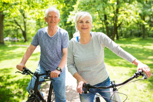 Casal sênior andar de bicicleta no parque — Fotografia de Stock