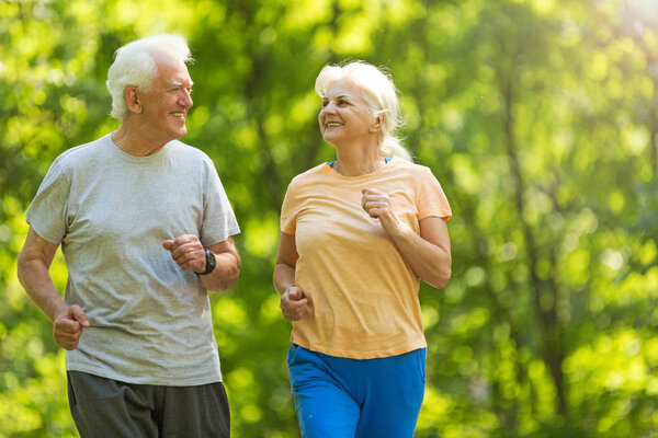Senior couple running in park