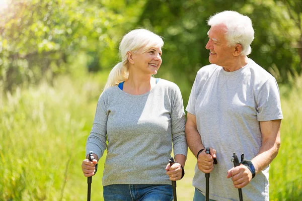 Senior couple nordic walking in park — Stock Photo, Image