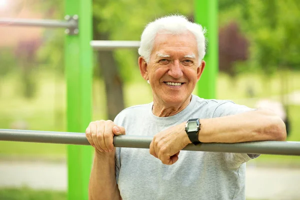 Senior man exercising at outdoor gym — Stock Photo, Image