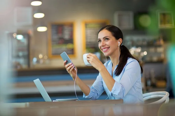Женщина пьет кофе во время работы над ноутбуком — стоковое фото