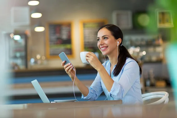 Vrouw koffie drinken terwijl u werkt op haar laptop — Stockfoto