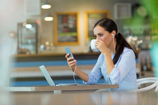 Kobieta pije kawę podczas pracy na jej laptopie — Zdjęcie stockowe