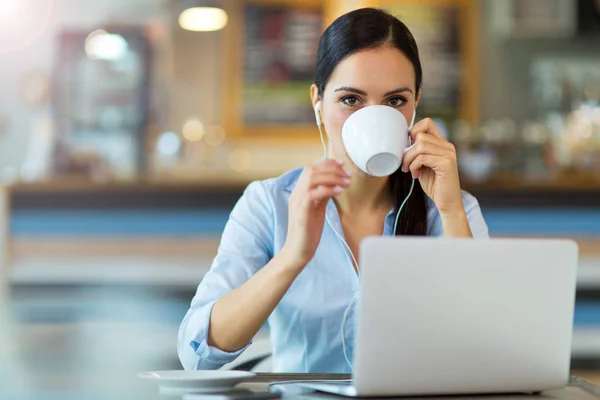 Frau trinkt Kaffee, während sie an ihrem Laptop arbeitet — Stockfoto