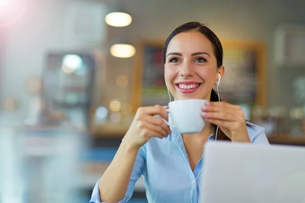 Mujer bebiendo café mientras trabaja en su computadora portátil — Foto de Stock