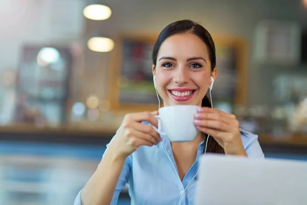 Mujer bebiendo café mientras trabaja en su computadora portátil — Foto de Stock