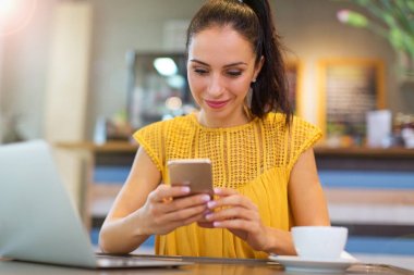 Café'de cep telefonu kullanan kadın