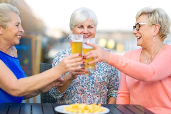 Sorridente donne anziane che bevono una birra in un pub all'aperto — Foto Stock