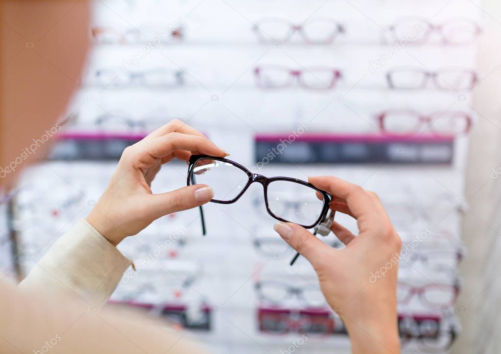 Woman choosing glasses in optician store