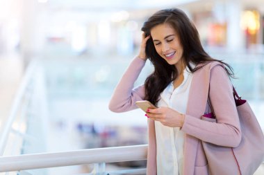 Alışveriş merkezinde cep telefonu kullanan bir kadın.