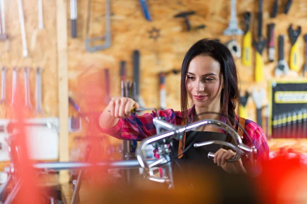 在自行车修理店工作的少妇 免版税图库照片