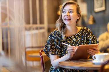 Female designer sketching with digital tablet and stylus at cafe